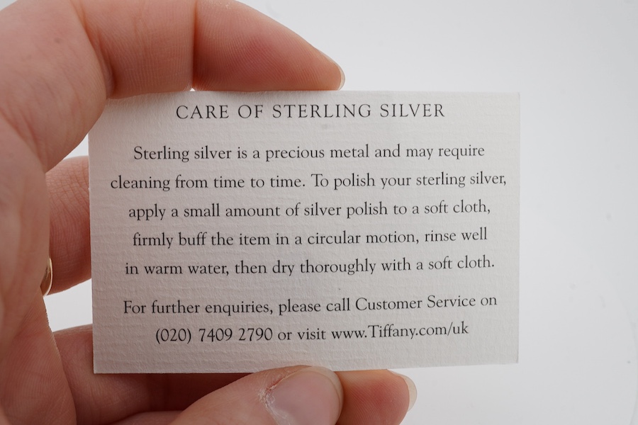 Tiffany & Co, a silver scarf ring, of torque design with a hanging tag, signed Tiffany & Co., British hallmarks, sponsor's mark T&Co., length 4.5cm excluding tag, gross weight 22 grams, pouch and box stamped Tiffany & Co